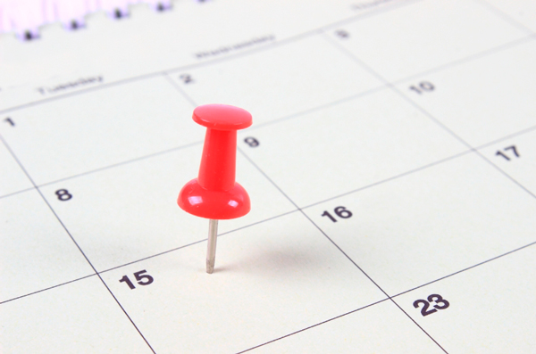 Um calendário com um pino marcando um dos dias.