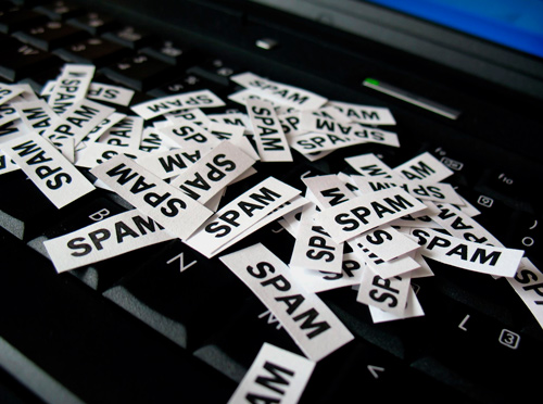 Teclado de computador com vários papéis escrito "spam" sobre ele.