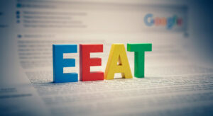 Sigla EEAT em frente uma página do Google embaçada.