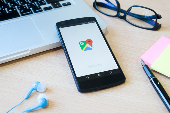 Smartphone sobre mesa de trabalho com aplicativos do Google aberto ao lado de laptop, em contexto de tecnologia e chatgpt.
