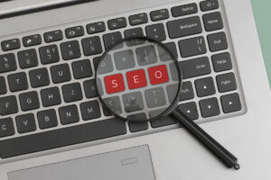 Lupa sobre teclado destacando a palavra SEO, representando estratégias de seo off page focadas em autoridade, backlinks e relevância externa para sites.