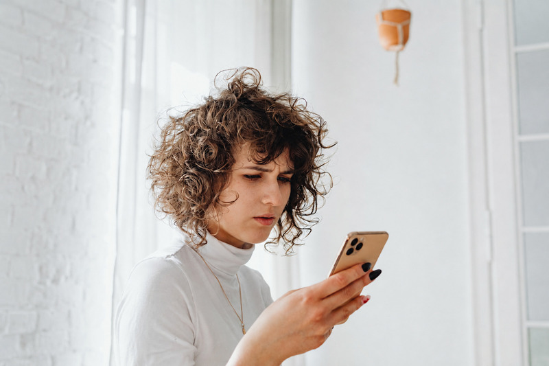 Conteúdo raso causando dúvida à possível cliente : mulher olhando no celular com cara de desconfiança